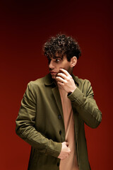 Stylish young man poses confidently against a vibrant red backdrop in a modern setting