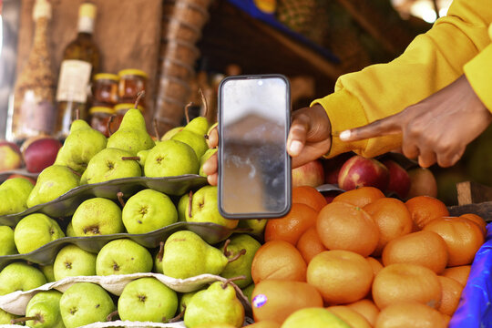 Fruit market scene with a person pointing at a smartphone