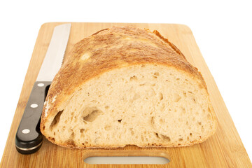 One half of a hearth bread on a bamboo board isolated on a white background, close-up.