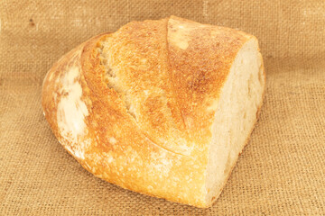 One half of a loaf of bread with a jute bag, close-up.
