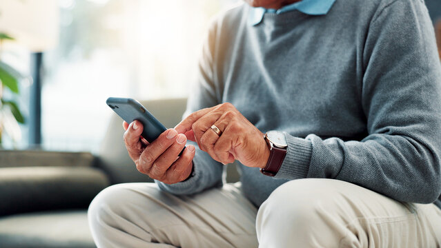 Senior man, hands and typing with phone on sofa for game, word search or social media app at home. Closeup, male person or elderly user browsing with mobile smartphone for connection or network - Powered by Adobe
