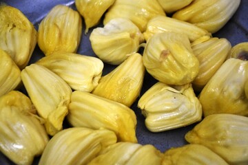 A close-up of an opened jackfruit showcasing its vibrant yellow fleshy pods surrounded by fibrous material. The detailed texture highlights the tropical fruit’s unique interior, making it ideal 