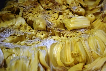 A close-up of an opened jackfruit showcasing its vibrant yellow fleshy pods surrounded by fibrous...