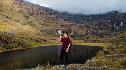 joven turista atractivo en América Latina, feliz mientras usa un teléfono inteligente mirada a un espacio publicidad y aislada en un fondo un lago naturaleza,contactar,celular,quechua