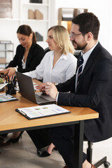 Coworkers working together at wooden table in office