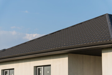 A sleek roof design on a contemporary house stands against a clear blue sky, showcasing architectural lines and modern aesthetics