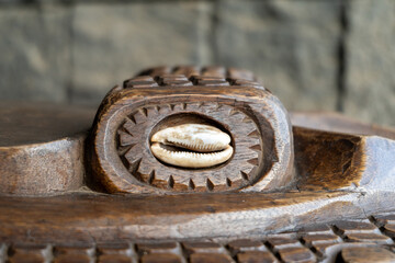 Close-Up of a Wooden Carving with Embedded Cowrie Shell and Tribal Ornamentation