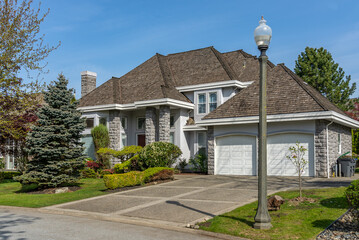 Two story stucco luxury house with nice spring blossom landscape in Vancouver, Canada, North America. Day time on April 2025