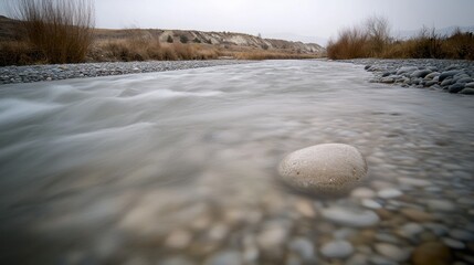 A flowing stream with pebbles and muted colors.