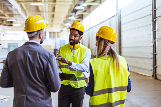 Construction Team Discussing Project Plans in a Modern Industrial Warehouse