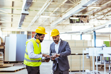 Industrial Meeting with Engineers Reviewing Construction Plans on a Factory Floor