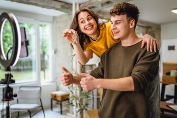 man and woman piggy back while record video and show keys of new home