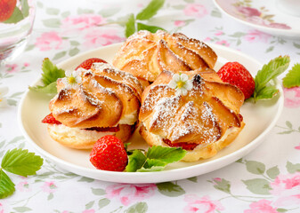 Cream puffs cakes or profiterole filled with whipped cream and strawberries