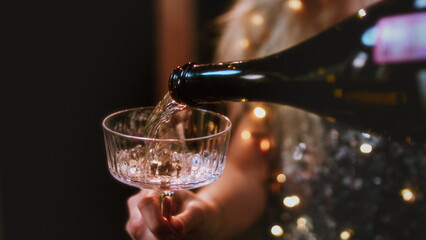 The girls pour champagne into round glasses. Women in a sparkling dress, cocktail creamers, le coupe
