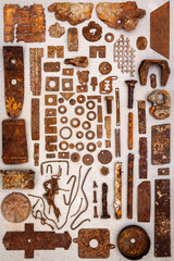 A group of various old rusty bits and pieces arranged on a concrete surface. Old rusty nuts, bolts, nails and other parts flay lay on gray background.