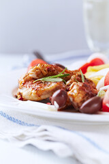 Spicy chicken wings with french fries and tomatoes. Close up.	