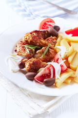 Spicy chicken wings with french fries and tomatoes. Close up.