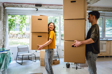 happy couple boyfriend and girlfriend moving boxes at their new home