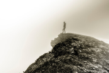 Ein Wanderer auf einem Felsvorsprung im Nebel