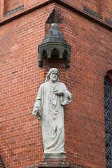 Obraz premium white stone statue of the holy prophet on the corner of a red brick catholic cathedral in germany