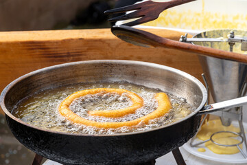 Dough frying in oil in outdoor cooking setup