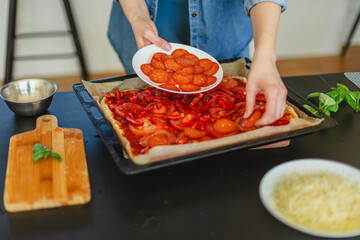 Cooking homemade pizza. Female hands making dough, adding sauce and ingredients.