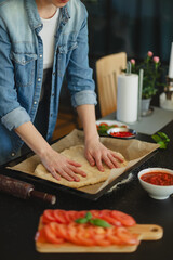 Cooking homemade pizza. Female hands making dough, adding sauce and ingredients.