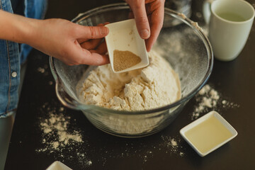 Cooking homemade pizza. Female hands making dough, adding sauce and ingredients.
