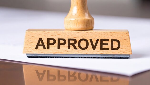 Business approval process close-up of approved rubber stamp on polished desk surface