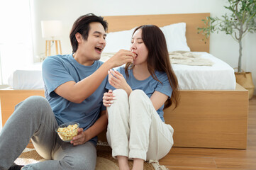 Couple Enjoying Popcorn Together While Sitting on the Floor in a Cozy Bedroom During the Afternoon