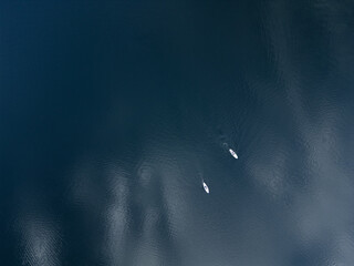 A drone view of the endless blue ocean with two white boats drifting. A scene of peace, space,...