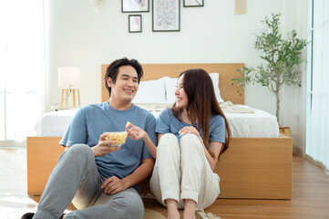 Couple Enjoying Popcorn Together While Sitting on the Floor in a Cozy Bedroom During the Afternoon