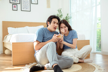 Couple Enjoying Popcorn Together While Sitting on the Floor in a Cozy Bedroom During the Afternoon