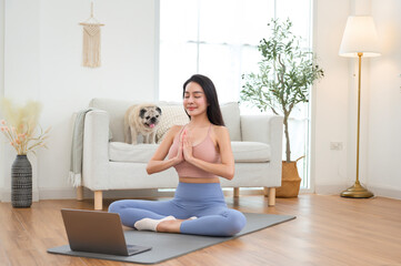 Woman Practicing Yoga at Home in a Serene Living Room With a Laptop and a Dog Nearby