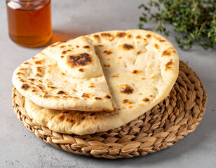 Emirati khameer flatbread served warm on a woven basket next to honey and thyme.