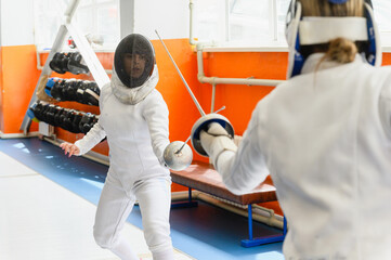 Female fencer facing opponent in close-up indoor duel.