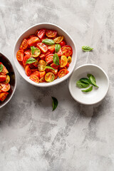 A light appetizer or an elegant side dish: a salad made with a mix of different tomato varieties, enriched with fresh basil and oregano leaves.