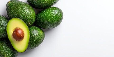 Ripe avocados, one halved, displayed on a white background with copy space, suitable for nutrition or culinary use