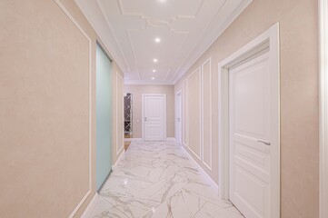 bright, elegant hallway with marble floors, neutral walls, a sliding door closet, and mirrored wall panels