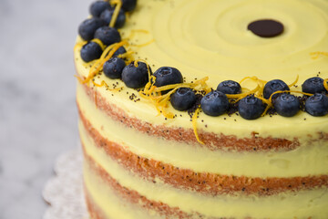 Elegant Lemon Blueberry Layer Cake a vibrant yellow lemon frosting, and a decorative topping of...