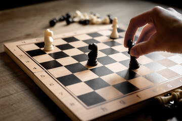 Hand is moving chess piece on chessboard. Game concept