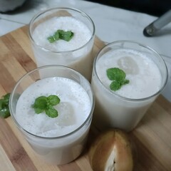 Creamy chikoo (sapodilla) milkshake served chilled in glasses, garnished with fresh mint leaves for a refreshing and healthy drink.