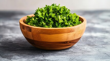 Bright green chopped parsley fills a wooden bowl sitting on a dark gray textured surface creating a visually appealing culinary image.