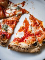Delicious pizza slices with melted cheese and savory toppings on a white plate, food concept. copy space