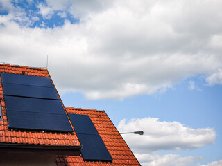 Solar panels installed on a modern rooftop against a backdrop of blue sky and fluffy clouds showcasing renewable energy solutions and sustainability concept