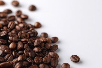 Naklejka premium Roasted coffee beans scattered on a white background.