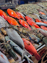 Assortment of fresh seafood including fish, shrimp, and lobsters at local market.