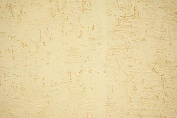 Close-up of textured yellow plaster wall showcasing a rough and uneven finish. Ideal for backgrounds, construction themes, or design elements requiring texture and warmth.
