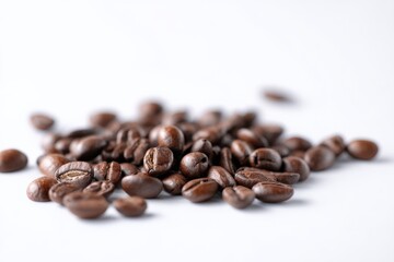 Fototapeta premium Roasted coffee beans scattered on a white background.