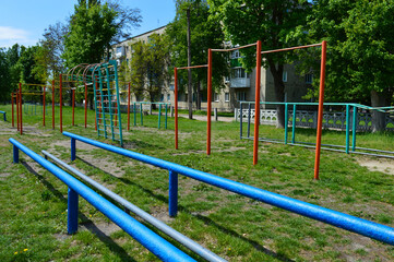 Outdoor workout playground with metal bars and climbing frames, old urban sports ground, sunny day,...